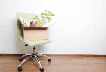 Box with personal items standing on the chair in the office.Concept of moving or dismissal