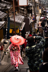 Japanese women wear kimonos and hold the red umbrella, walk on the streets in markets around tourists.
