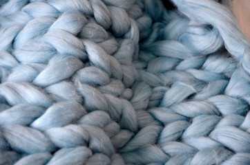 Merino wool handmade knitted large blanket, super chunky yarn, trendy concept. Close-up of knitted blanket, merino wool background