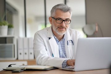 mature doctor in office working on laptop computer