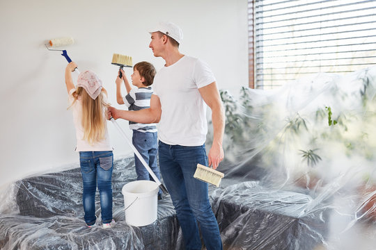 Kinder streichen Wand bei Renovierung im Eigenheim