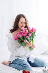 Portrait of young woman with pink tulips. White shirt