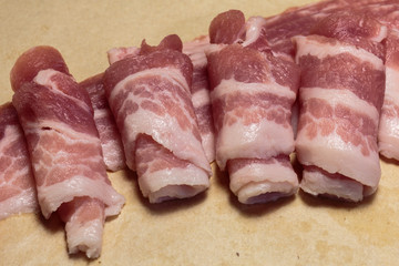 Raw rolls of bacon, close-up, ready for cooking.
