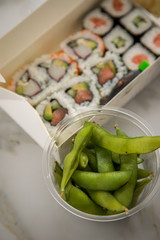 Edamame, Maki und Inside Out California Sushi vom Lieferdienst mit Lachs, Surimi, Avocado, Gurken mit Ingwer, Wasabi und Soja Soße in Einweg Bento Box Verpackung