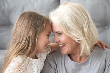 Happy grandmother and granddaughter embracing, touching foreheads