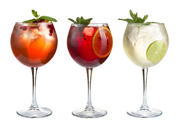 Alcohol cocktail with mint, fruits and berries on a white background. A set of three cocktails in glass goblets on a long stem.