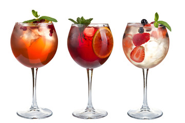 Alcohol refreshing cocktails with mint, fruits and berries on a white background. A set of three cocktails in glass goblets on a long stem.