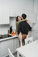 beautiful young smiling couple hugging in kitchen during breakfast