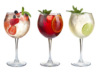 Alcohol refreshing cocktails with mint, fruits and berries on a white background. Set of three cocktails in glass goblets.
