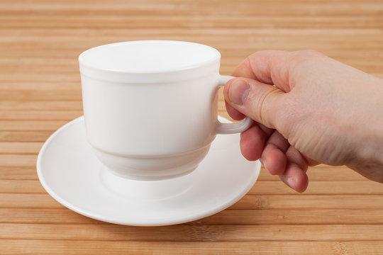 Hand holding cup on wooden background