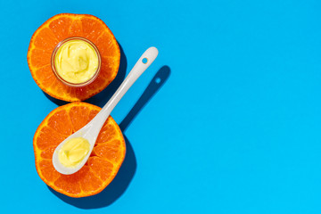 Face cream and orange on a bright blue background. Cosmetics from natural ingredients natural concept