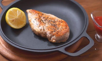 Large chicken fillet with lemon baked in a frying pan