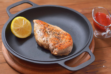 Large chicken fillet with lemon fried in a pan