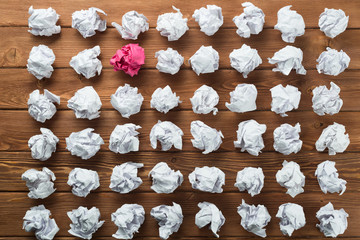 Concept of creativity and inspiration presented by many white paperballs and one color