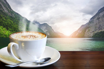 Cappuccino on the table with blur landscape of lake and mountain