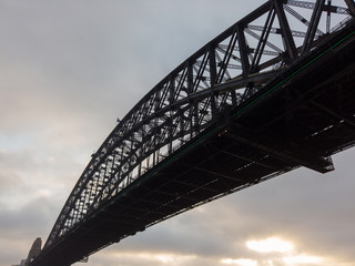 Sydney Harbour Bridge view from below with cloudy sky.