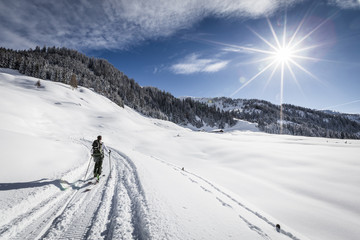 Traumhafte Winterlandschaft mit Wintersportler und Sonne
