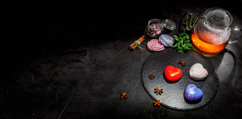 Three sweet desserts in the shape of a heart heart with mirror glaze on dark background with copy space