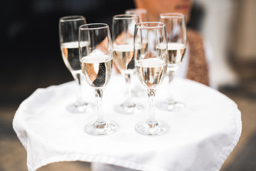 Waiter serving glasses with champagne on a tray