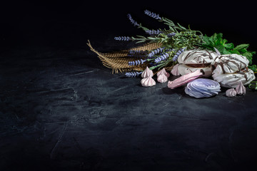 Heap of sweet meringue mixed with flowers on dark background with copy space