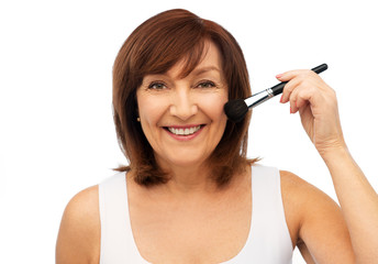Fototapeta premium beauty, make up and old people concept - smiling senior woman with blush brush over white background