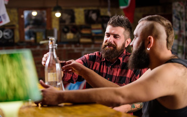 Hipster brutal man drinking alcohol with friend at bar counter. Men drinking alcohol together. Strong alcohol drinks. Friends relaxing in pub. Alcohol addiction. Men drunk relaxing at pub having fun