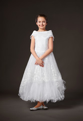 Fototapeta premium little girl is dressed in a white ball gown, dark background