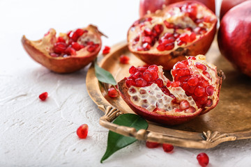 Metal tray with ripe pomegranates on white background