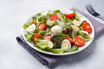 Fresh salad with tomatoes and quail eggs and lettuce.
