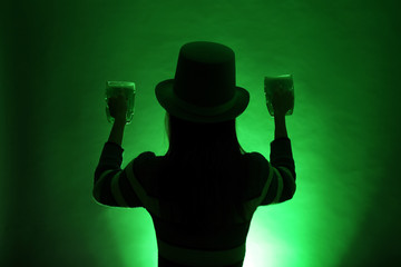 Silhouette of woman with beer on dark color background. St. Patrick's Day celebration