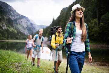 Group of smiling friends hiking with backpacks outdoors. Travel, tourism, hike and people concept.