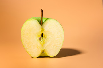 Sliced green delicious apple isolated on orange background, contrast shadows