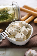 Bowl with tasty feta cheese and garlic on table