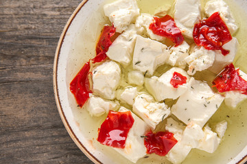 Plate with tasty feta cheese, chili pepper and olive oil on wooden table, closeup