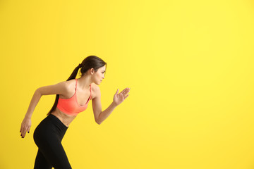 Fototapeta na wymiar Sporty young woman running against color background