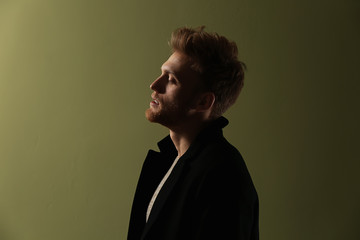 Fashionable young man on color background