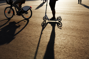 silhouette kick scooter, silhouette of a man and a bicycle wheel with backlight. Long contrasting...