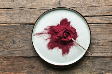 Plate with acai powder on wooden background