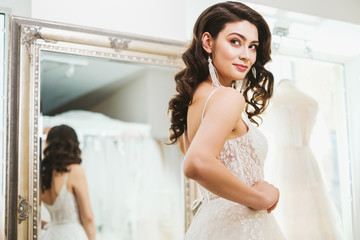 Naklejka premium Beautifu bride choosing wedding dress in a wedding salon