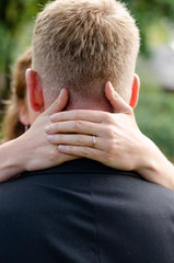 Woman's hand around her partner's neck, with the focus on her engagement ring