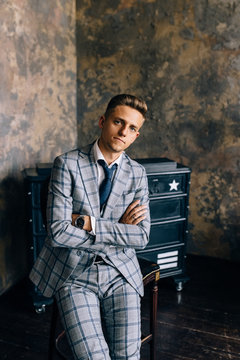 A man in a blue suit is sitting on a chair