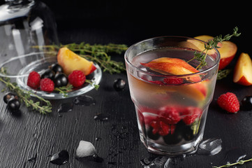 Raspberry thyme gin and tonic cocktail with blackcurrant and peaches