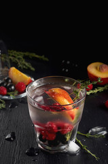 Raspberry thyme gin and tonic cocktail with blackcurrant and peaches