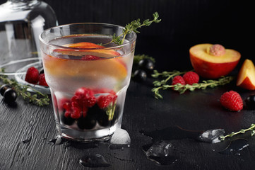 Raspberry thyme gin and tonic cocktail with blackcurrant and peaches