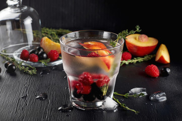 Raspberry thyme gin and tonic cocktail with blackcurrant and peaches