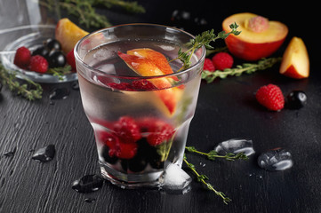 Raspberry thyme gin and tonic cocktail with blackcurrant and peaches