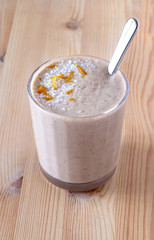 Healthy organic date, banana and apple milk smoothie powdered shreded coconut and orange zest. Fresh diet breakfast. Wooden background. Selective focus.