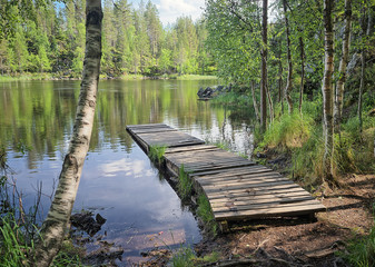 Landscape with a dock or a pier on the lake on a sunny summer day. Oulanka National Park, Kuusamo, Finland. Wild calm nature of the North for recreation and fishing.