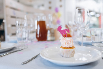 Delicate and delicious muffin with cream and pink paper unicorn decoration