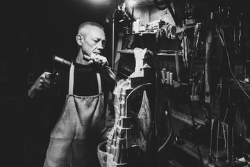 Master carpenter 50 - 55 years old works with wood in the workshop, black and white photography
